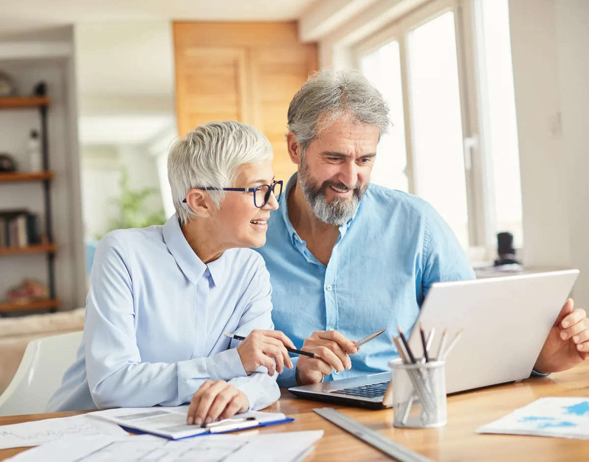 Senior couple working together on a laptop at a home desk