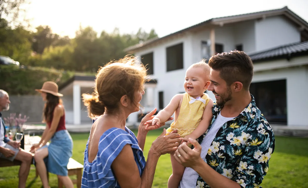 Family celebrating in a suburban garden as a father holds a laughing baby