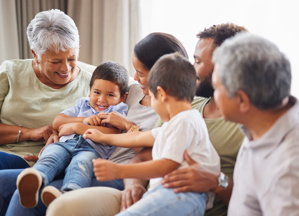 Multigenerational family playing with two young children on a couch