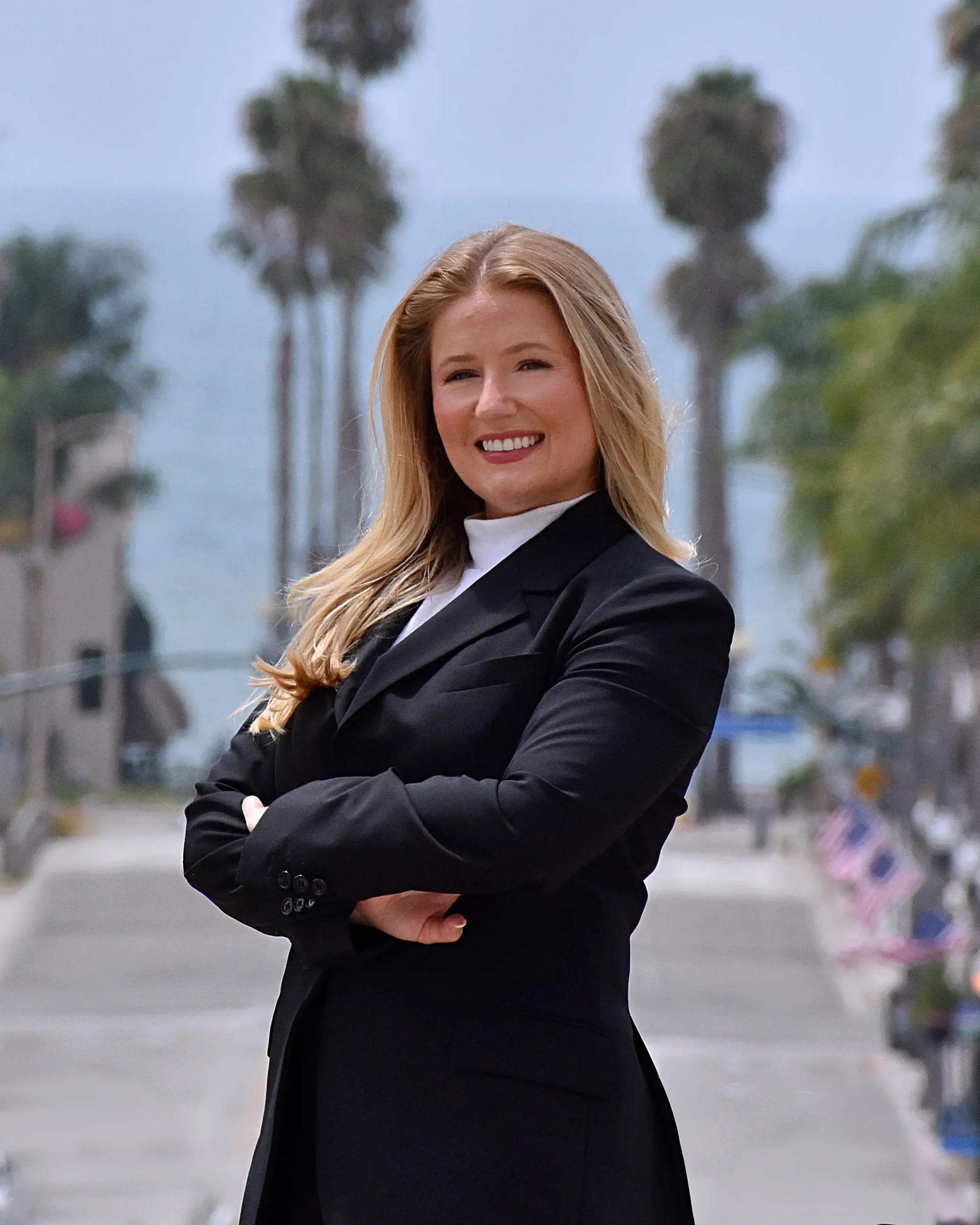 Siena M. Martinez, Esq., attorney at Siena Law, P.C., on a palm-lined street in Southern California