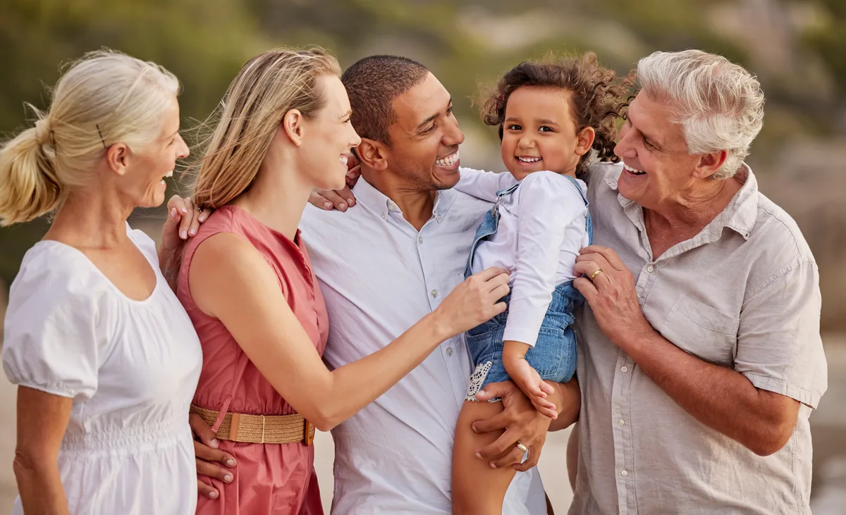 Multigenerational family laughing together with a toddler outdoors