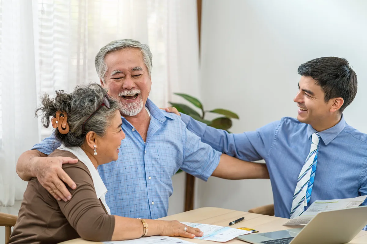 Senior couple smiling as they meet with an advisor at their kitchen table